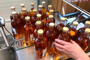 Bild aus der Abfüllung der Distillery Krauss. mehrere gefüllte Rumflaschen mit goldenem Verschluss.